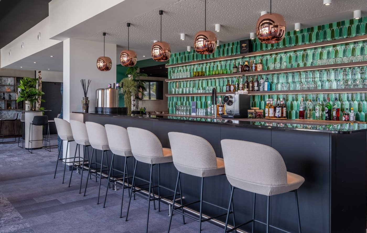 Bar du Kyriad Châteauroux Nord Aéroport avec fond de carrelage vert et suspensions cuivrées
