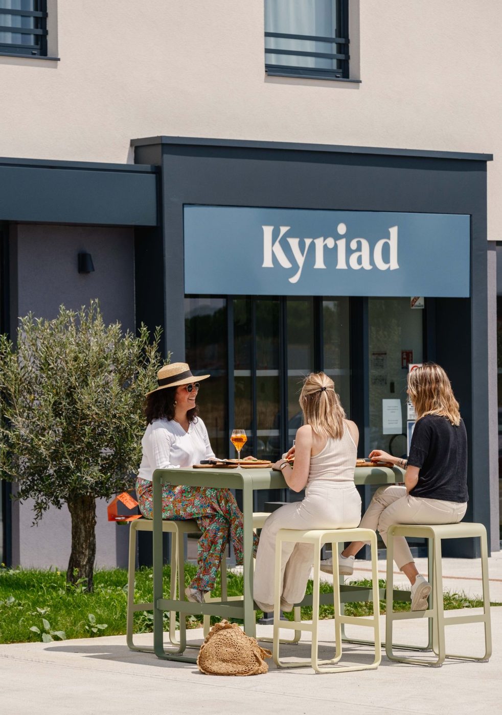 Entrée et terrasse du Kyriad Châteauroux Nord Aéroport, trois personnes attablées autour d’un apéritif